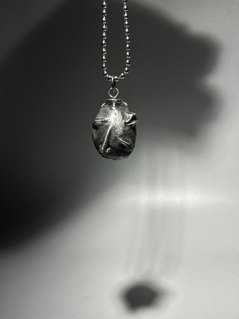 Handcrafted Behelit Pendant Necklace – Choirchain creation with high-quality pewter. Unique, hand-cast, and finished pendant with subtle imperfections showcasing authenticity. Suspended on a sleek stainless steel 22-inch (55.9 cm) 2.0mm ball chain with lobster claw closure. Adjustable length for comfortable wear. Premium collectible jewelry, symbolic of destiny and transformation. Perfect for fans of legendary tales, unique gifts, statement pieces, and meaningful accessories. Raw charm, exclusive artisan cr