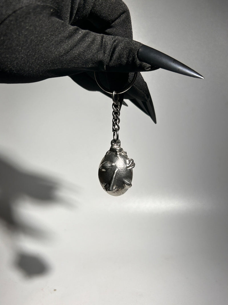 Handcrafted Behelit Keychain – Cast from solid, lead-free 97LF alloy pewter with a stainless steel chain and iron split ring. Unique, hand-finished charm with subtle imperfections, symbolizing dark fantasy and artistry. 4.25-inch (11 cm) drop length, perfect for Berserk fans, collectors, and admirers of symbolic accessories. Durable and distinctive design for daily use or display.