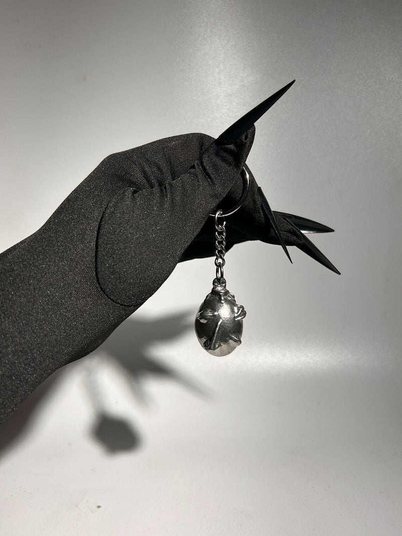 Handcrafted Behelit Keychain – Cast from solid, lead-free 97LF alloy pewter with a stainless steel chain and iron split ring. Unique, hand-finished charm with subtle imperfections, symbolizing dark fantasy and artistry. 4.25-inch (11 cm) drop length, perfect for Berserk fans, collectors, and admirers of symbolic accessories. Durable and distinctive design for daily use or display.