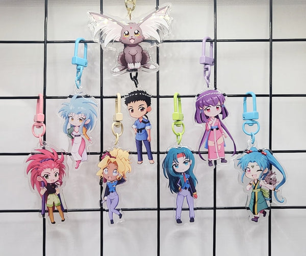 Exclusive Tenchi Muyo acrylic keychain featuring double-sided designs of Ryo-Ohki, Tenchi, Sasami, Ryoko Hakubi, Washu, Ayeka, Mihoshi, and Kiyone. Vibrant, scratch-resistant colors with a glitter epoxy coating for a standout look. Perfect for accessorizing backpacks, lanyards, and Ita bags. Durable silver D-clasp for long-lasting use. A must-have collectible and a perfect gift for Tenchi Muyo and anime fans!