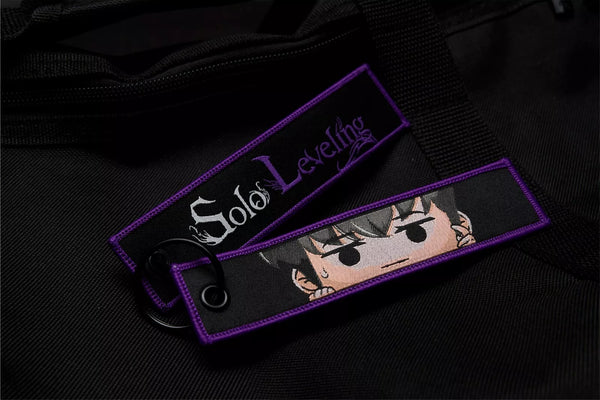 Solo Leveling: Ore dake Level Up na Ken Embroidered Jet Tag featuring Chibi Sung Jin-Woo, the Shadow Monarch symbol, and his iconic dual daggers. Crafted from durable, high-quality materials with bold, double-sided embroidery, this jet tag perfectly captures the intense action and dark fantasy of Solo Leveling. Perfect for keys, backpacks, or cars, this collectible is a must-have for fans of Sung Jin-Woo’s journey and anime enthusiasts who love epic leveling-up stories. Show off your love for Solo Leveling